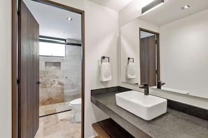Een moderne badkamer met een grote spiegel, een witte wastafel en een douchehoek.