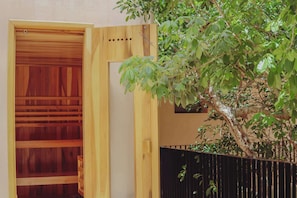 Une porte en bois dotée d’un panneau coulissant, une clôture en métal noir et un arbre aux feuilles vertes.
