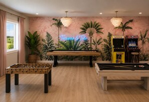 A room with a pool table, foosball table, and arcade games. - Butler Beach | Heated Pool + Theater + Ocean Views (St. Augustine)