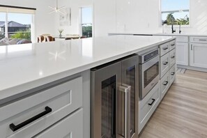 A modern kitchen with white cabinetry, stainless steel appliances, and a large island. - Steps to Beach + Private Pool, Theater & Arcade (St. Augustine)