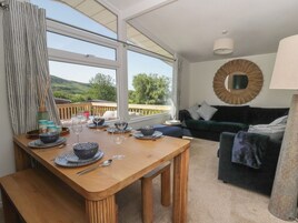 Un comedor con una mesa de madera dispuesta para dos, un sofá y vistas al exterior.