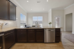 A modern kitchen with dark cabinetry, a central island, and a dishwasher. - Executive Corporate Retreat CW | Work-Friendly (Midland)