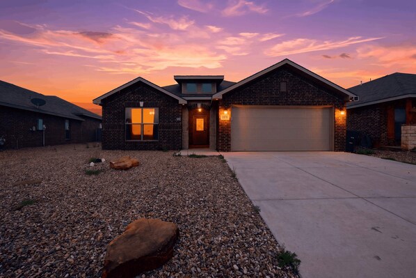 A two-story house with a garage, a driveway, and a gravel front yard. - Executive Corporate Retreat CW | Work-Friendly (Midland)