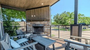 An outdoor patio with stone and wood furniture, a fireplace, and a view of the street.