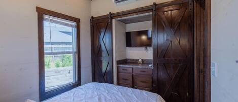 Une chambre à coucher comprenant un lit, une fenêtre, un bureau intégré et une armoire avec une porte de placard miroir.