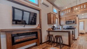 A modern kitchen with a fireplace, a large TV, and a bar area.