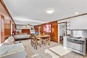A compact kitchen with a stove, dining area with a table and chairs, and a living area with a sofa and a TV.