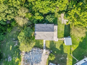 An aerial view of a property with a large building, a dock, and surrounding greenery.