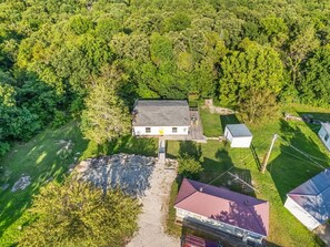 Vista aérea de una propiedad con una casa principal, un edificio más pequeño y un patio cercado.