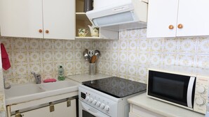 Une cuisine de taille réduite, équipée d’une cuisinière, d’un four à micro-ondes et d’un évier.