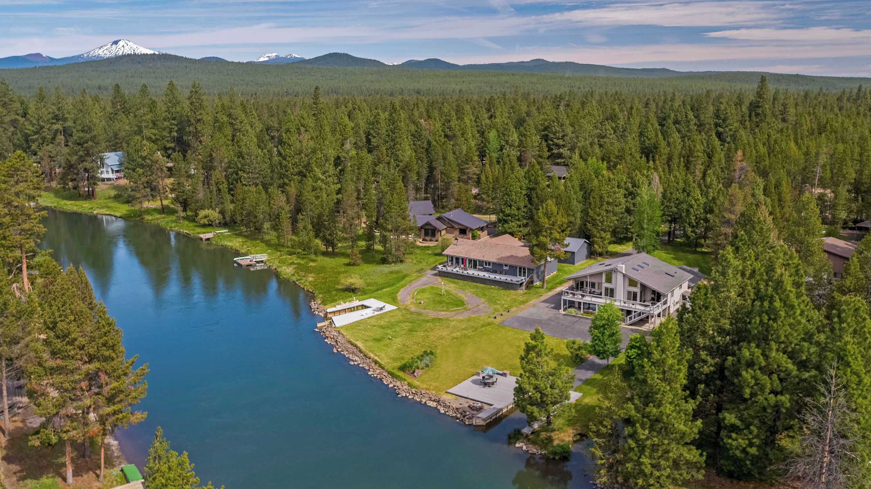 A lakeside property with multiple houses, a dock, and a mountain in the background.