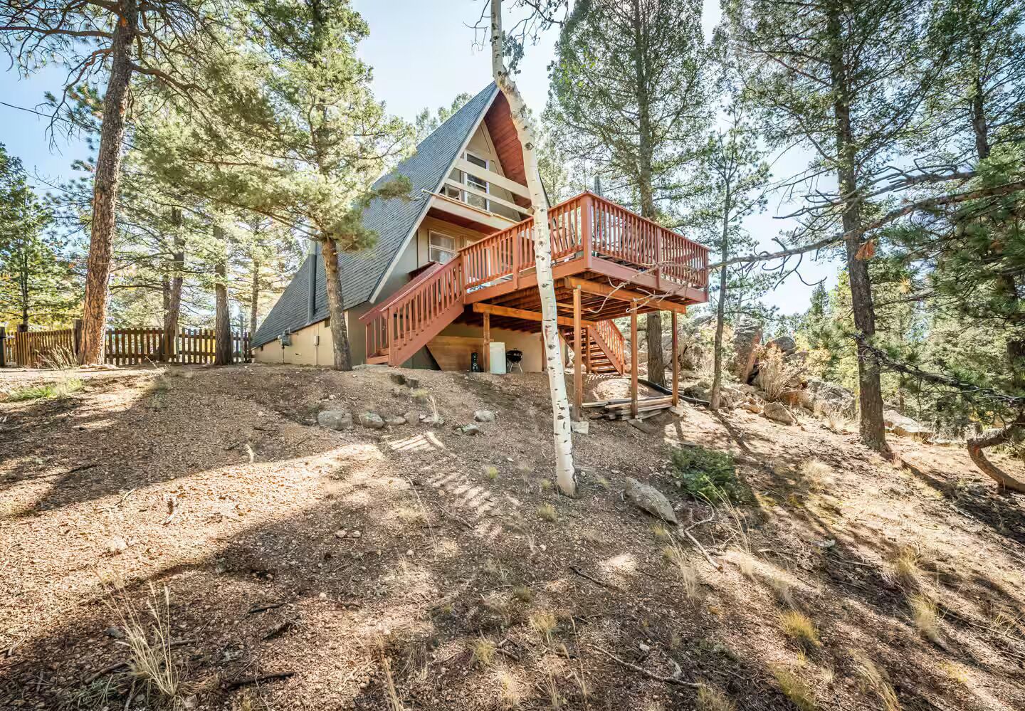 A cabin with a wooden deck, surrounded by trees.