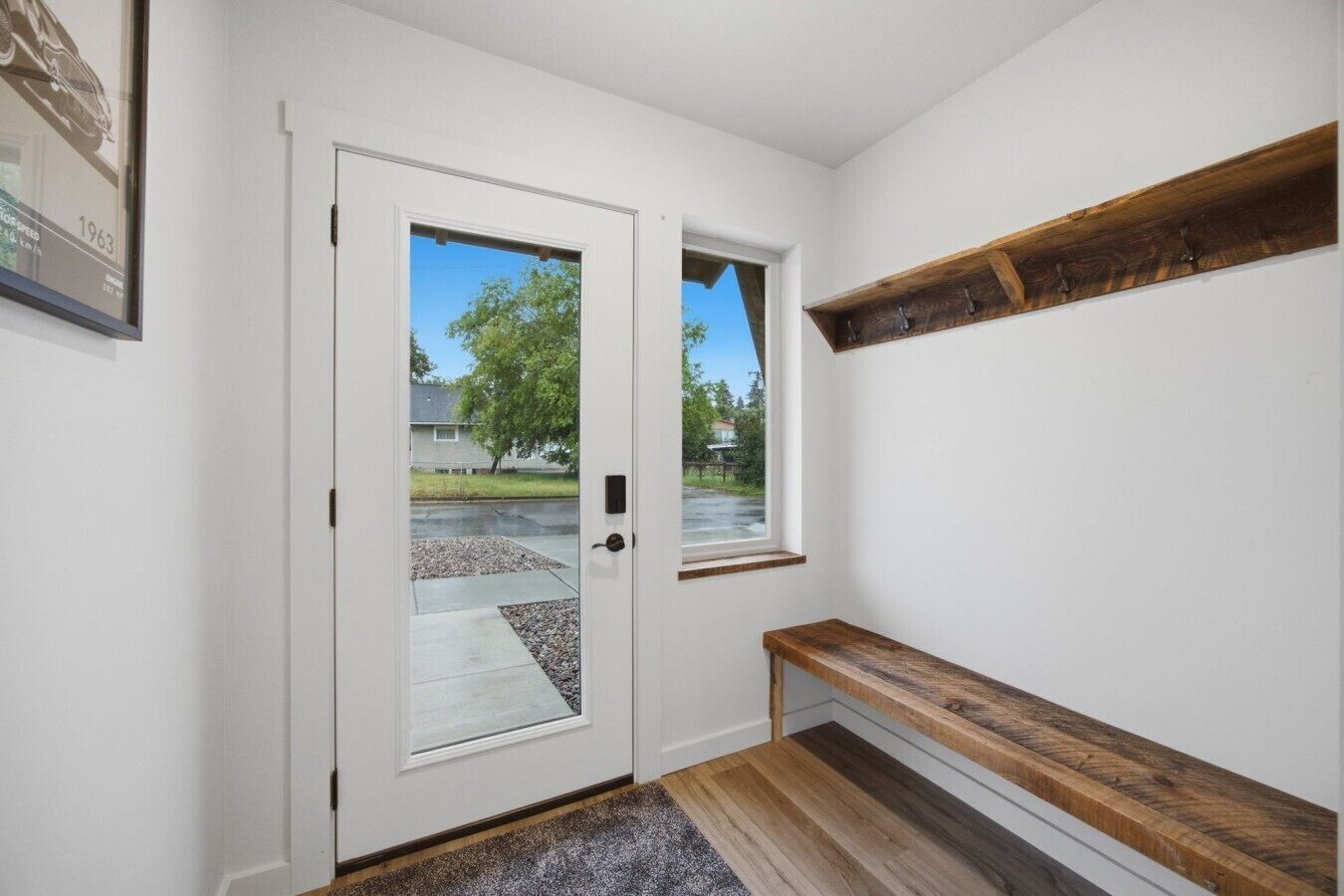 En hall med en vit dörr, en bänk och en hylla i trä.