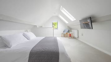 A bedroom with a bed, a chair, a small table, a radiator, and a window.