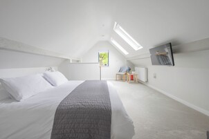 Un dormitorio con cama, una silla, una mesita y un radiador, además de un ventanal.