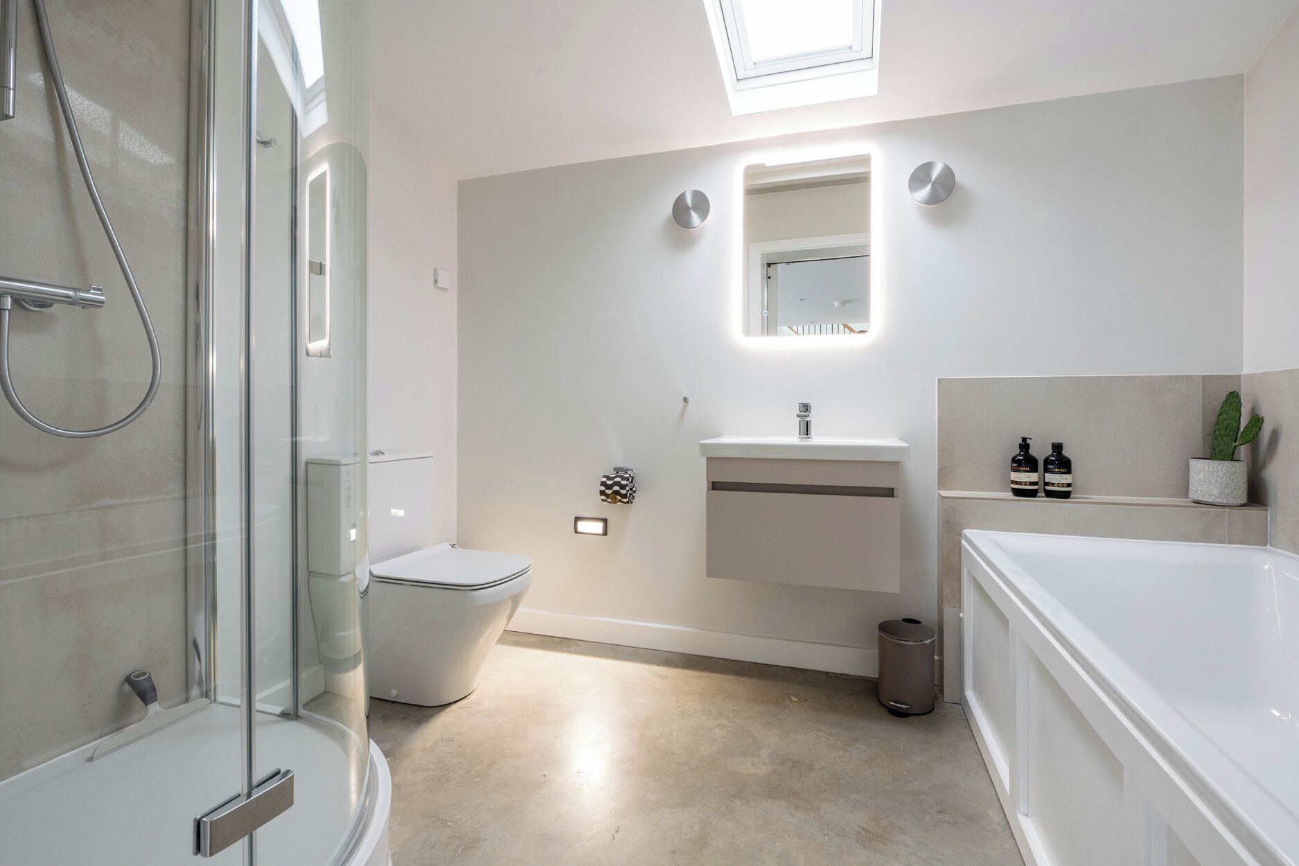 Une salle de bain moderne avec une douche à parois de verre, des toilettes, un lavabo avec un miroir et une baignoire.