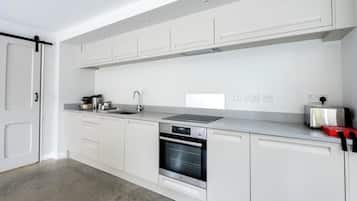Een moderne keuken met witte kasten, een roestvrijstalen oven, een spoelbak en een broodrooster.