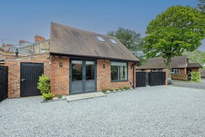 A modern brick house with a sloped roof, large windows, and a gravel driveway.