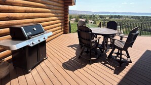 Een houten terras met een barbecue en tuinmeubilair.