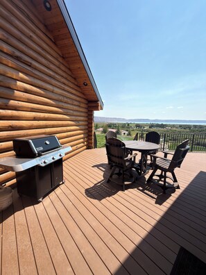 Eine Holzterrasse mit Grill und Gartenmöbeln.
