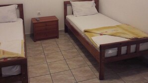 A small, clean room with two single beds, a nightstand, and a tiled floor. - Triple room with it's own bathroom and balcony. (Budva)