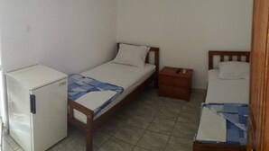 A small, single-room accommodation with a bed, a small table, a nightstand, and a refrigerator. - Triple room with it's own bathroom and balcony. (Budva)