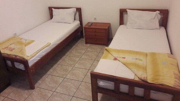 A room with two single beds, a wooden nightstand, and a tiled floor. - Triple room with it's own bathroom and balcony. (Budva)