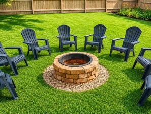 A backyard with a circular stone fire pit surrounded by six Adirondack chairs.