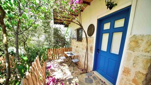 A stone building with a blue door, a wooden fence, and a table with chairs outside.