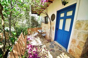 Un edificio de piedra con una puerta azul, una valla de madera y una mesa con sillas afuera.
