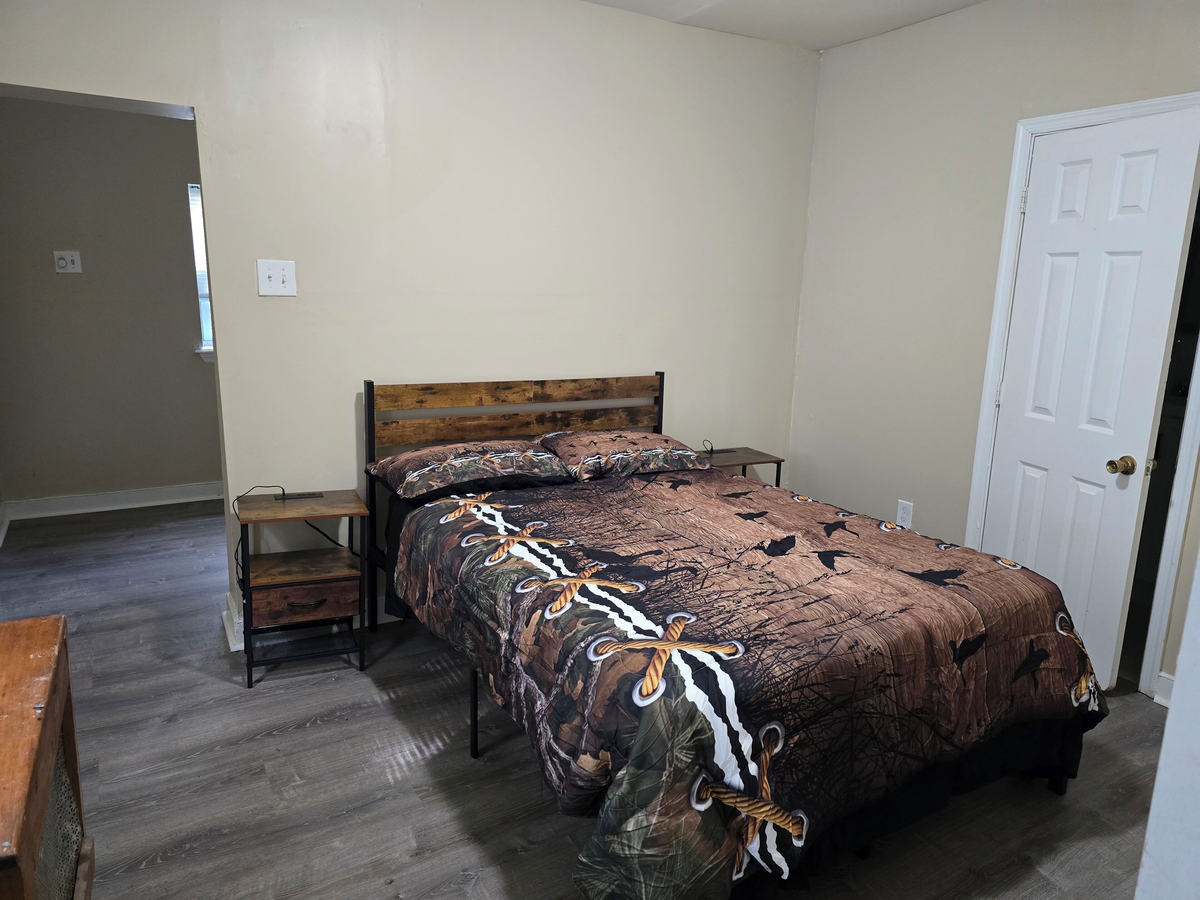 A bedroom with a wooden bed, a nightstand, and a door.