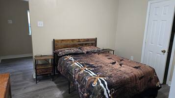 A bedroom with a wooden bed, a nightstand, and a door.