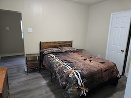 A bedroom with a wooden bed, a nightstand, and a door.