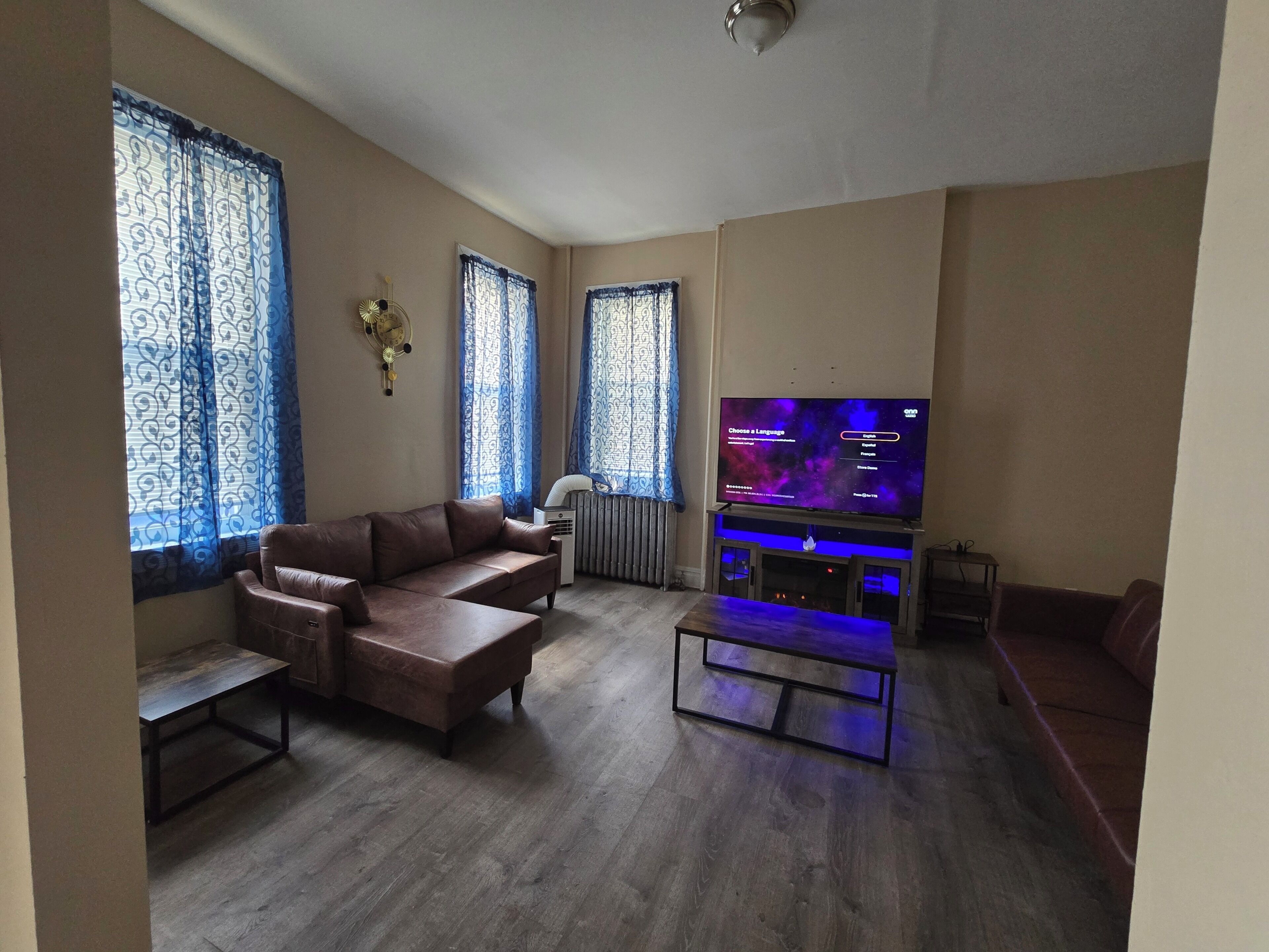 A living room with a brown leather sofa, a flat-screen TV, and a wooden coffee table.