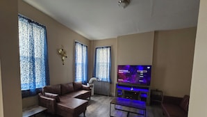 Una sala de estar con un sofá de cuero marrón, un televisor de pantalla plana y una mesa de centro de madera.
