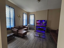 Una sala de estar con un sofá de cuero marrón, un televisor de pantalla plana y una mesa de centro de madera.