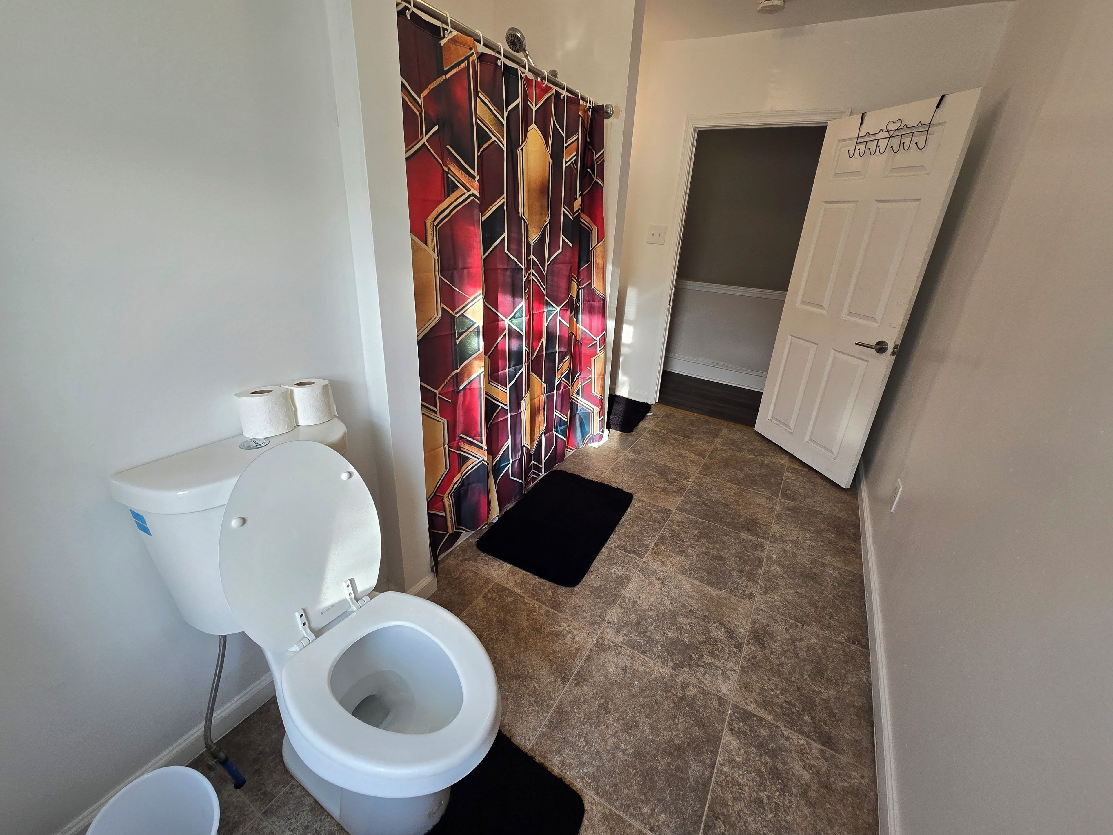 Un baño con inodoro, cortina de ducha y puerta.