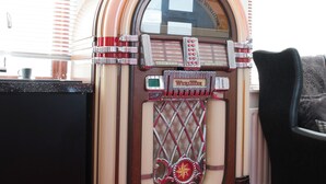 En gammal jukebox med en glaspanel, en gitarr och inramade skivor på väggen.