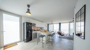 Et moderne køkken med en central ø, barstole og et spiseområde med bord og stole.
