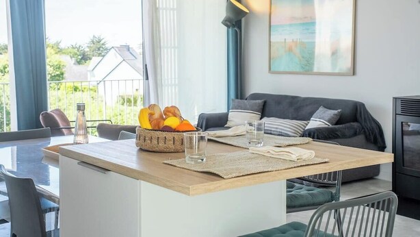 En moderne stue med en sofa, et spisebord med en kurv med frugt, og et billede på væggen.