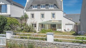 A two-story house with a conservatory, stone wall, and a small garden with plants and flowers. - Le Grand Large : Maison de Maître face mer (Penmarch)