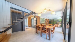 A modern interior with a staircase, dining area, and large windows.