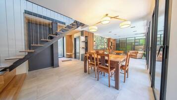 Een modern interieur met een trap, eethoek en grote ramen.