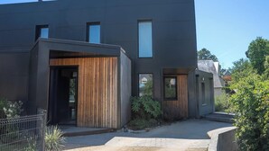 A modern building with a flat roof, large windows, and a wooden entrance.
