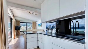 Una cocina moderna con encimera negra, armarios blancos y vistas a la ciudad.