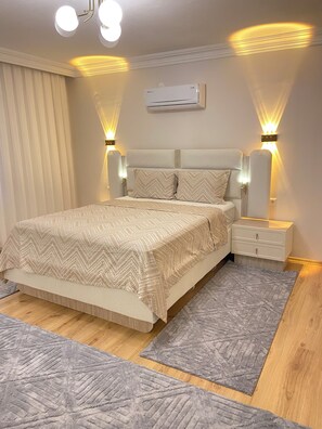 Ein Schlafzimmer mit einem Bett, Nachttischen, einer Klimaanlage und Wandleuchten.