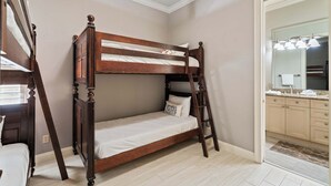 Un letto a castello con una scala, un bagno con uno specchio e un lavandino, e un corridoio con una ventola a soffitto.