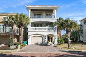 A two-story residential building with a garage, a balcony, and a driveway. - Ocean Manor - 4 Bikes, Shared Pool, Pet Friendly! (Destin)