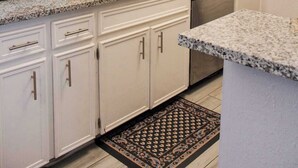Uma cozinha com armários brancos, micro-ondas, pia e backsplash.