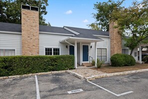 A two-story building with a brick chimney, a covered entrance, and a parking lot.